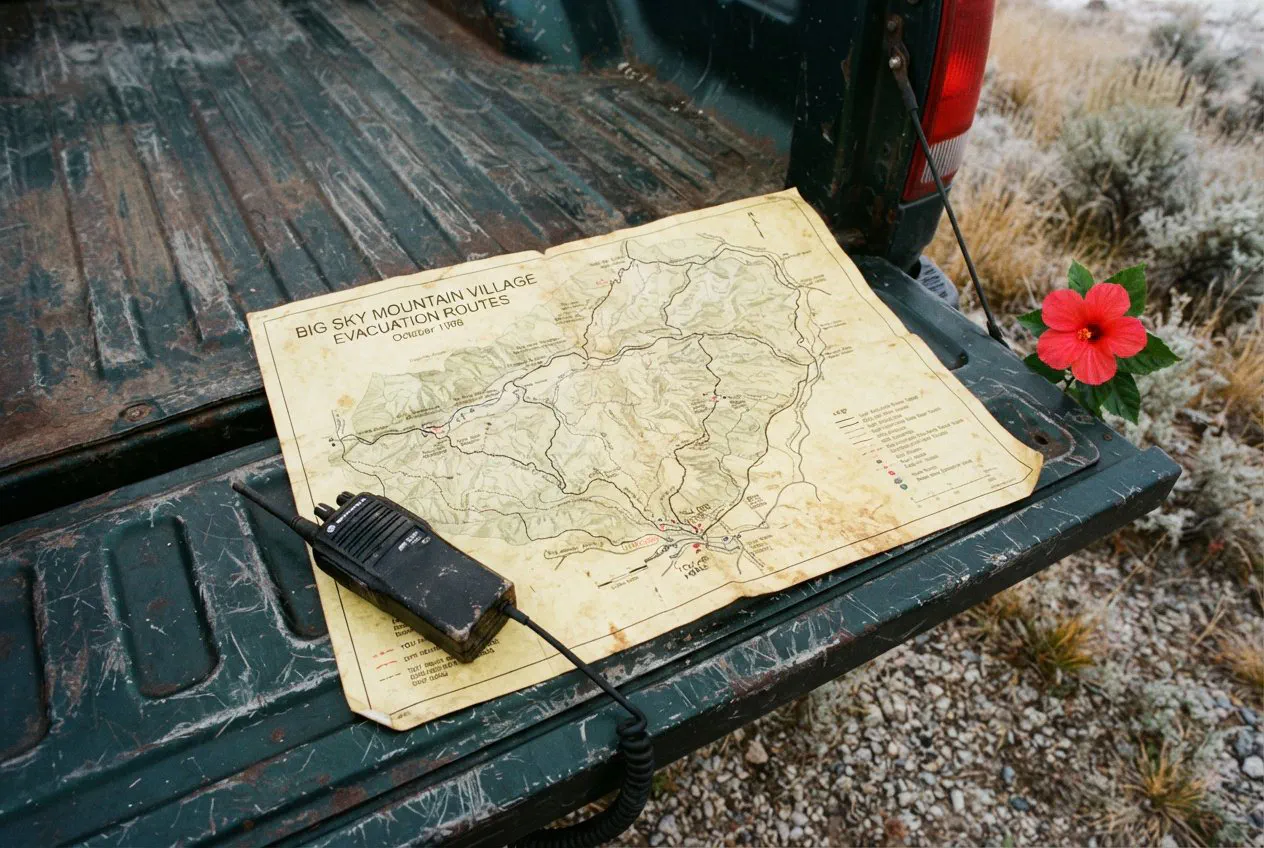 A close-up, top-down shot of a weathered, yellowing evacuation route map for the Big Sky Mountain Village, spread flat across the scratched, dark-green steel