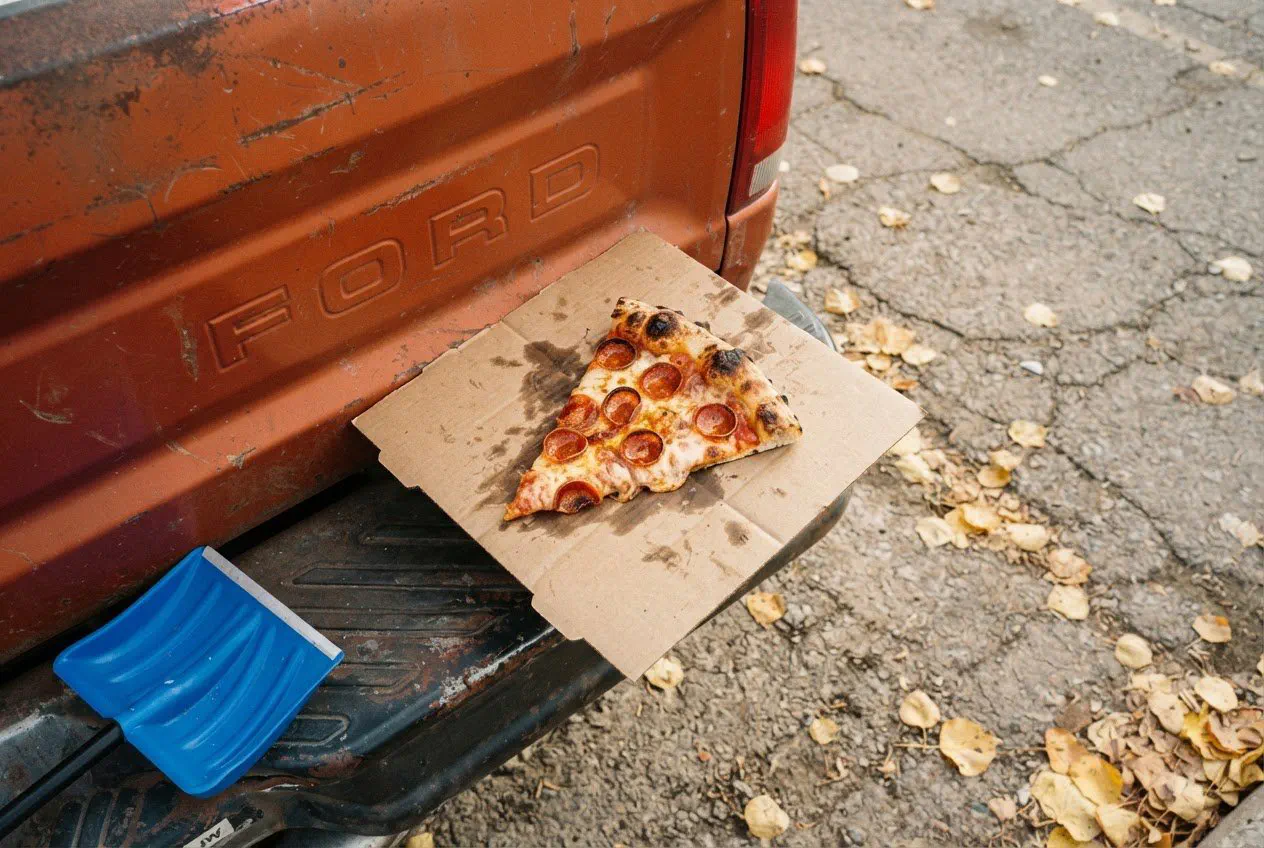 A close-up, top-down shot of a single slice of pepperoni pizza resting on a grease-stained cardboard square.